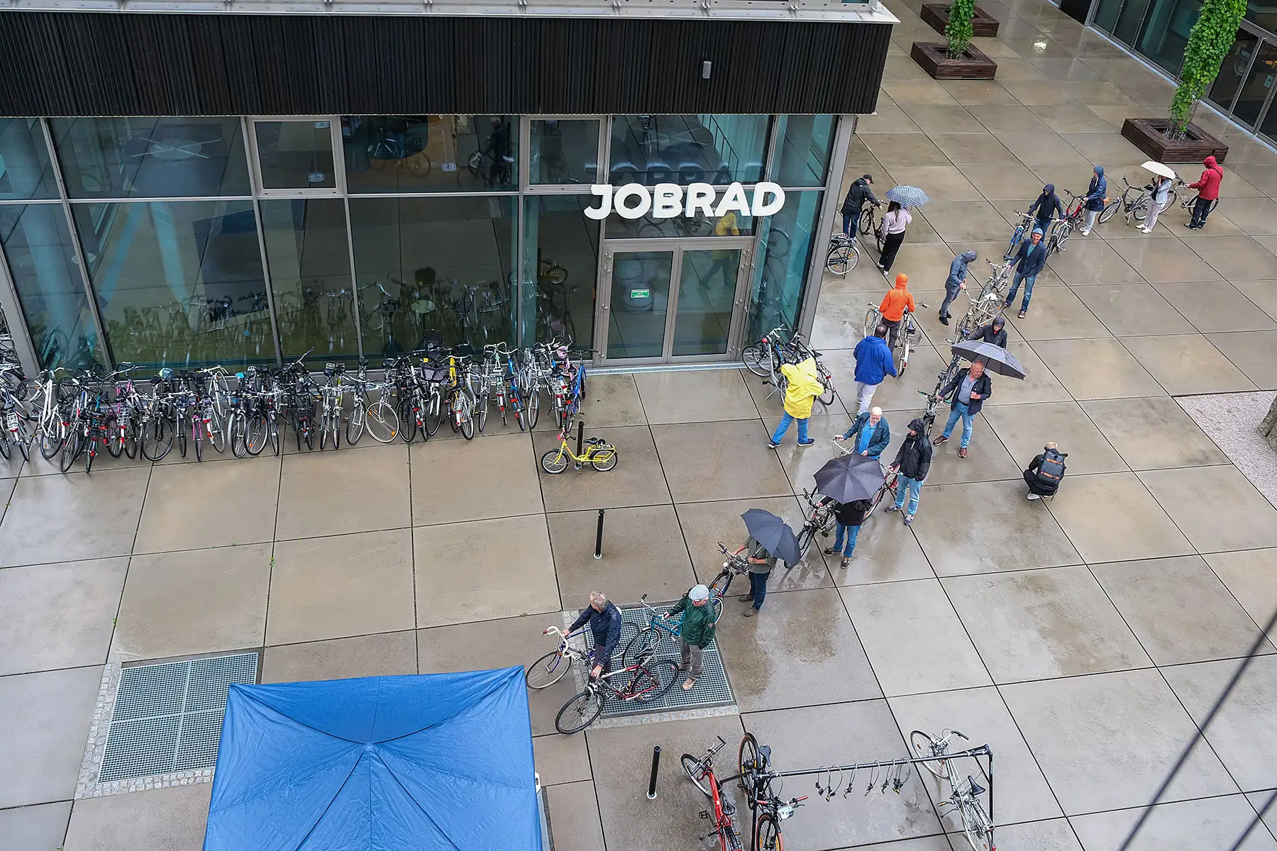 Eine lange Schlange von Menschen mit Fahrrädern und Regenschirmen auf dem JobRad Campus